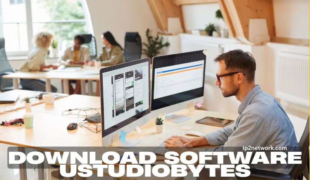 A professional man working on dual monitors in a modern office, using creative and analytical tools in UStudioBytes software, with colleagues collaborating in the background — concept for Download Software UStudioBytes from ip2network.com.