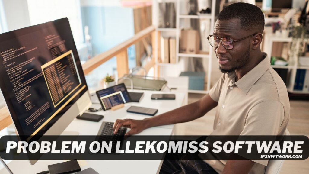 A man wearing glasses sits at a desk working on a computer with code displayed on a large monitor. Several devices, including a laptop, tablet, and phone, are on the desk. The text “Problem on Llekomiss Software” is overlaid across the bottom of the image.
