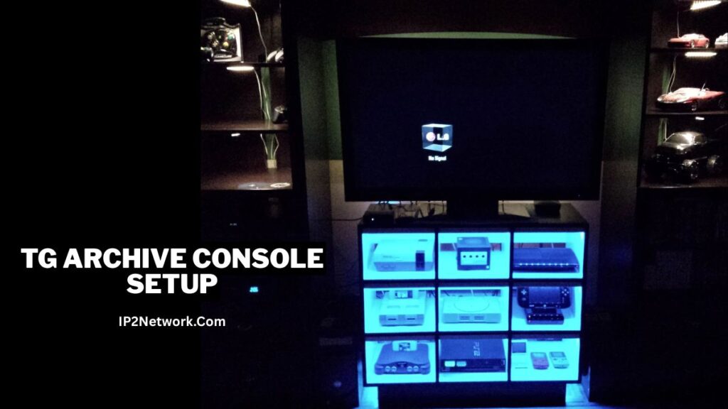 A dark room featuring a large LG television displaying a “No Signal” message. Below the TV is a backlit shelving unit glowing blue, showcasing multiple retro and modern game consoles including an NES, GameCube, PlayStation, Nintendo 64, PlayStation 2, and a Wii U GamePad. Car models are displayed on illuminated shelves to the left and right. Text on the left side reads “tg archive console setup” and “IP2Network.com.”